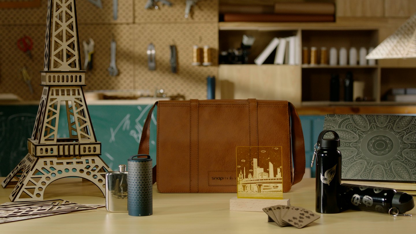Laser-cut wooden and metal crafts displayed on a workbench.