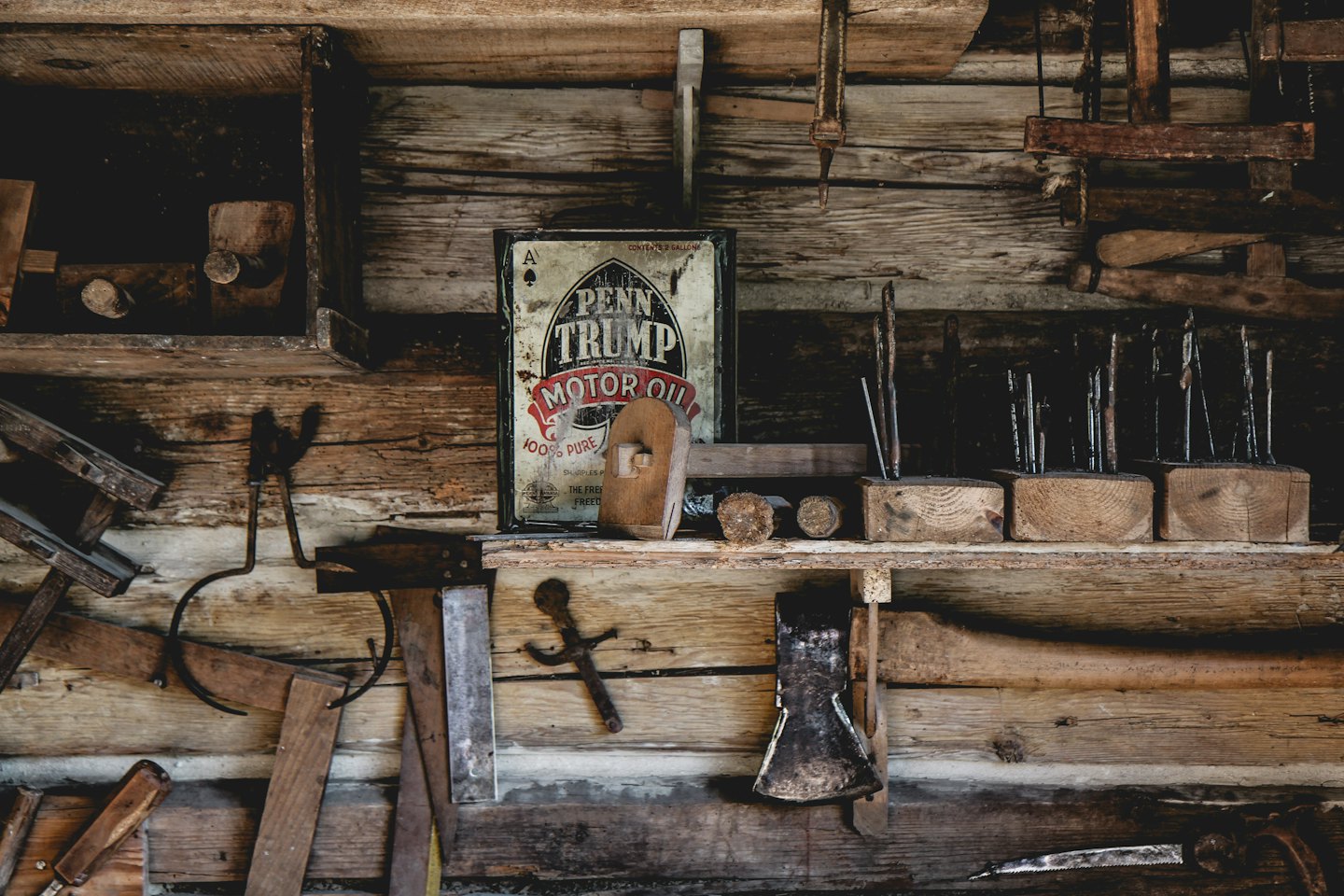 Rustic workshop wall with shelves of vintage tools and metal sign.