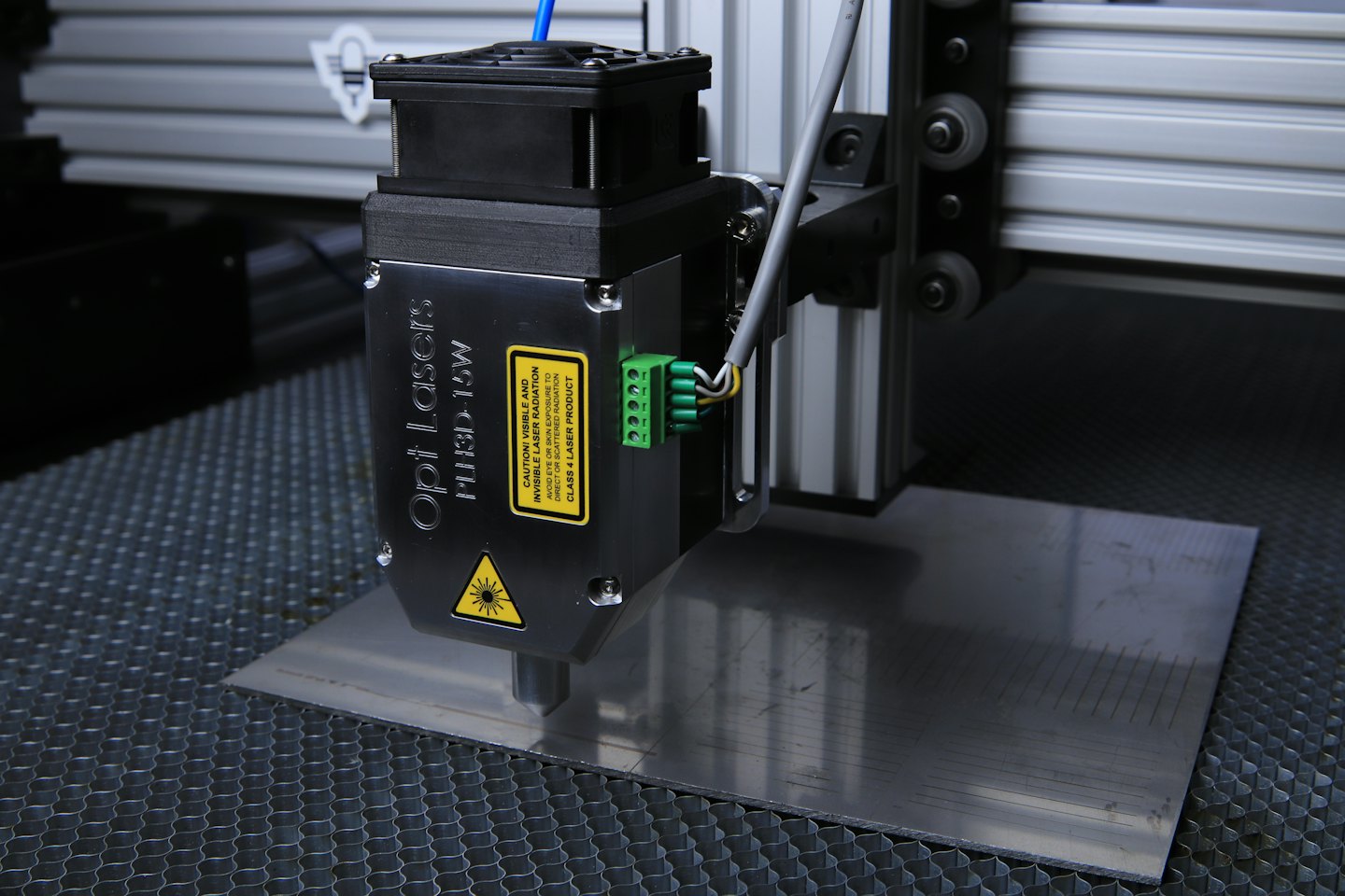 Laser engraver marking lines on brushed metal surface.